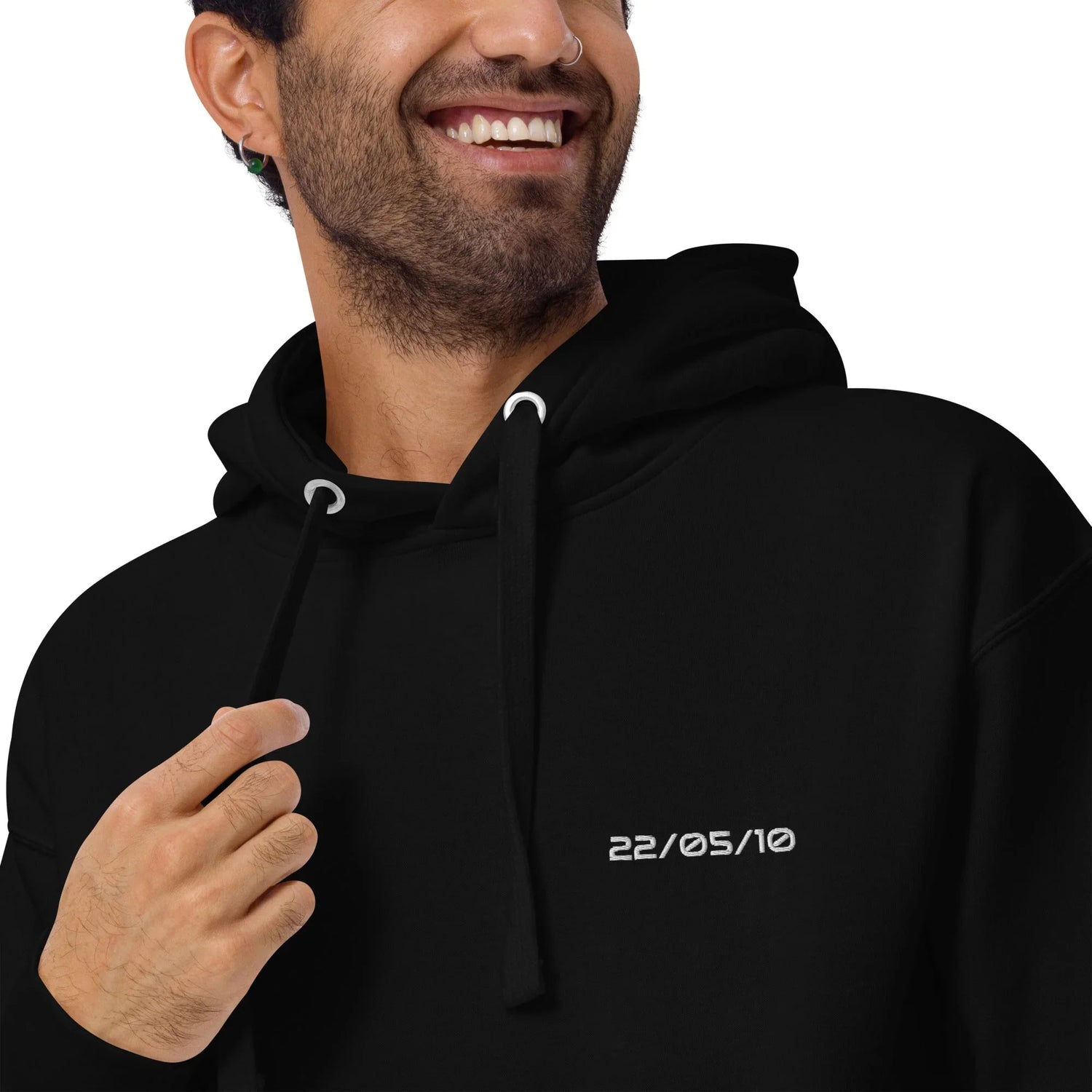 Nahaufnahme eines lächelnden Mannes in schwarzem Premium-Hoodie mit weißer Datumsstickerei 22 05 10